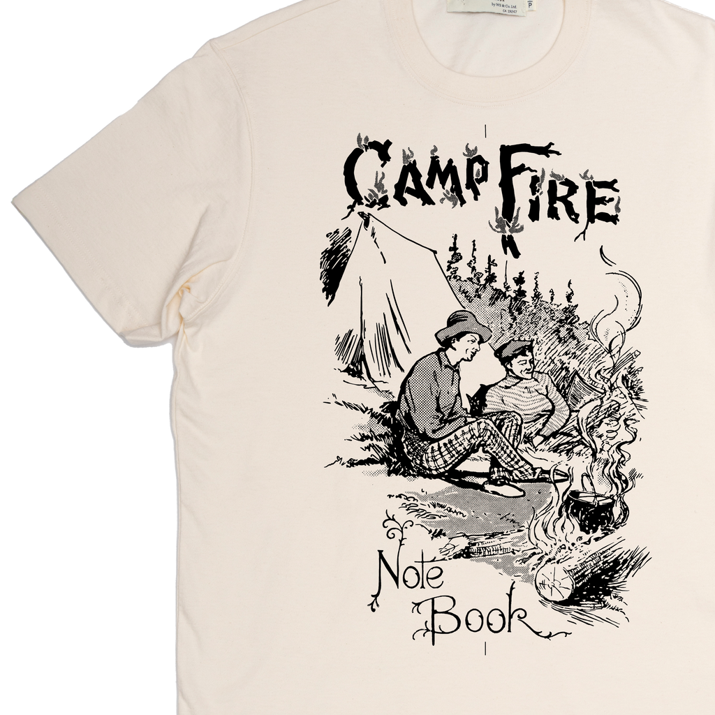 Beige t-shirt with black graphic design of two people by a campfire and text 'Camp Fire Note Book'.